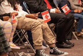 People sitting in chairs hold Canadian flags